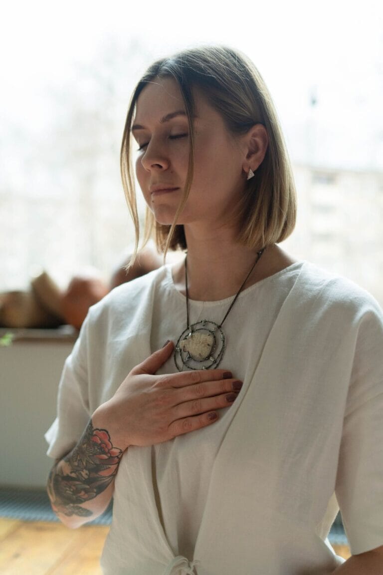 Woman with eyes closed and hand on chest, breathing calmly